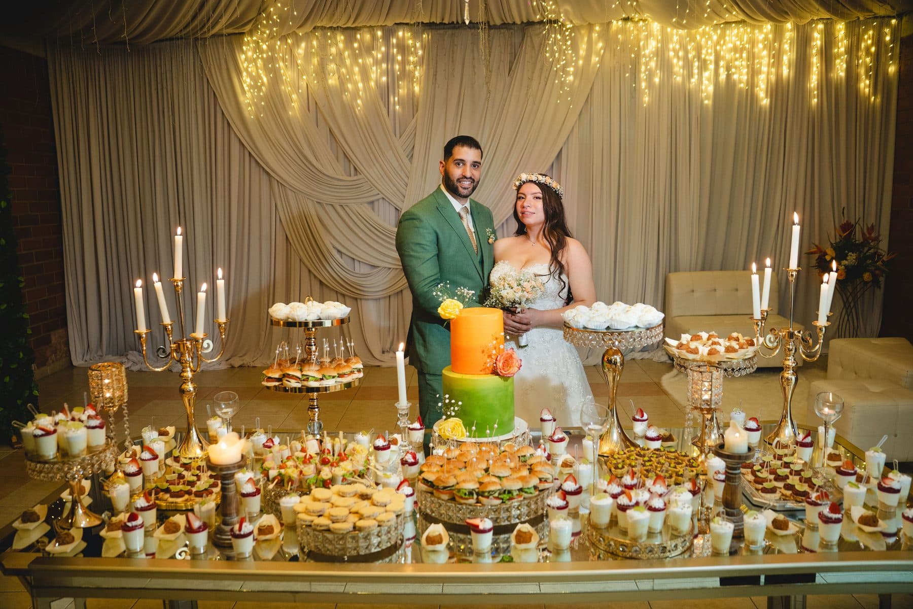 Luisa y Josué junto a la mesa de postres con candelabros, en una boda Premium