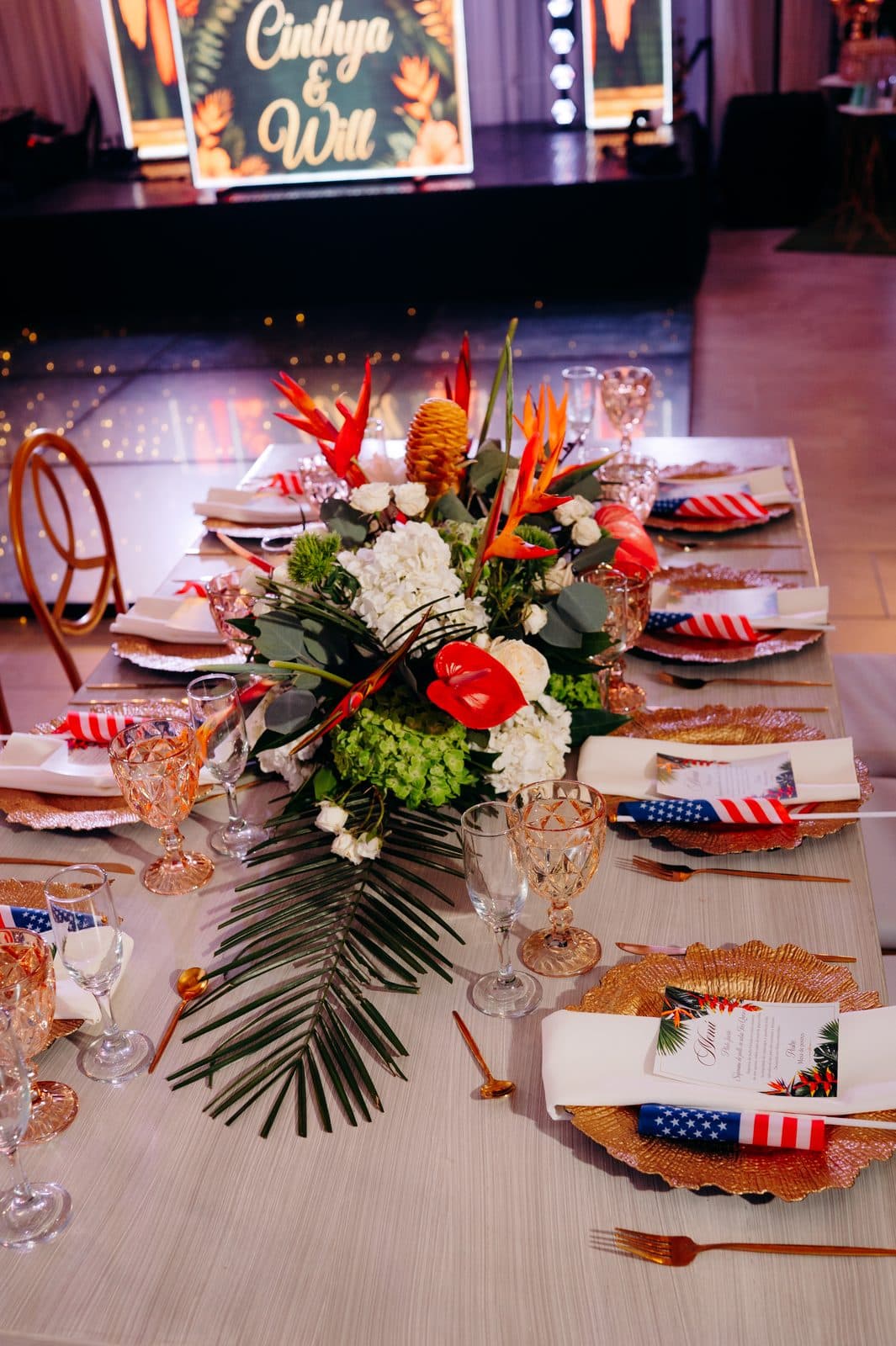 Mesa con centro de flores tropicales y banderas de Colombia y Estados Unidos