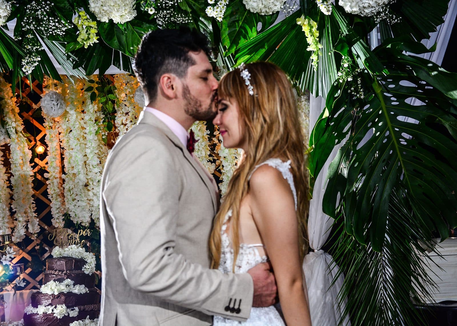 Alejandro besa a Alejandra en la frente frente a su arco de flores