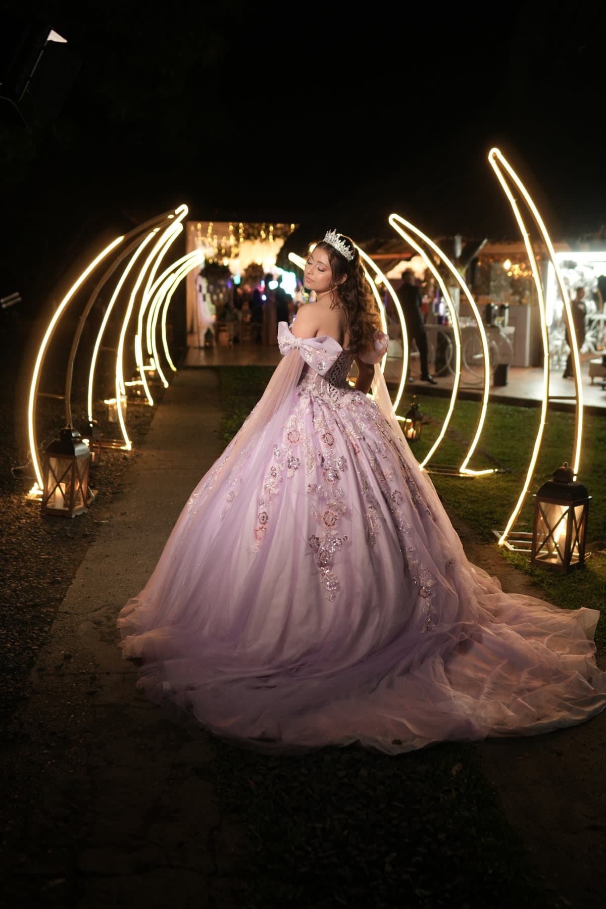 María Camila caminando de noche bajo arcos de luz